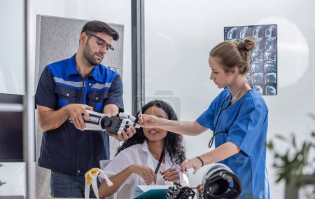 Foto de Ingeniero de rehabilitación robótica trabaja con un médico ortopédico y un cirujano para crear brazos y manos robóticas somatosensoriales para pacientes que requieren prótesis avanzadas o apoyo de rehabilitación. - Imagen libre de derechos