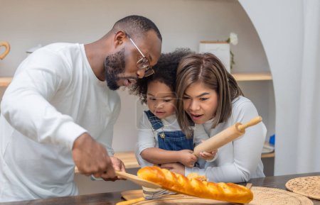 Photo for A family of three, with a father, mother, and daughter, delight in baking and sharing bread at home. - Royalty Free Image