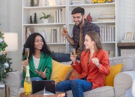 Foto de A diverse group of multicultural coworkers enjoys drinks and socializes in a relaxed, stylish living room after successful work party. Their friendly gathering fosters togetherness, bonding, teamwork - Imagen libre de derechos