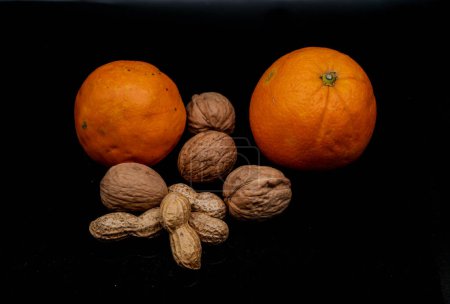 Photo for Studio photo on black background of fresh and dried fruit. oranges, peanuts and walnuts in an Italian study - Royalty Free Image