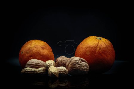 Photo for Studio photo on black background of fresh and dried fruit. oranges, peanuts and walnuts in an Italian study - Royalty Free Image