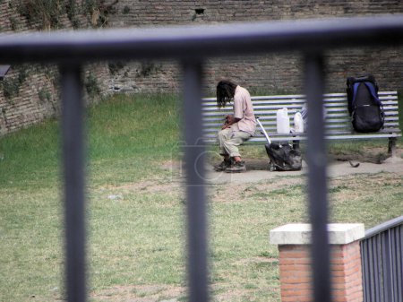 Photo for Disadvantaged, marginalized person. a homeless man in a park in Rome drowns his sorrows in alcohol among the people around him - Royalty Free Image