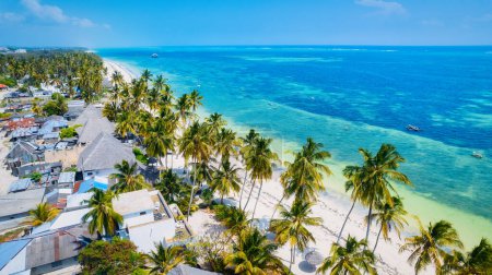 Photo for Zanzibar Island boasts a stunning tropical beach featuring white sand, palm trees, and turquoise waters against a backdrop of a clear blue sky with fluffy clouds on a sunny summer day. This picturesque setting is perfect for a relaxing vacation. - Royalty Free Image