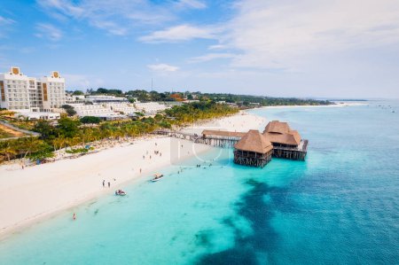 Foto de Una vista aérea de las playas de arena de Zanzíbar captura la esencia de un paraíso tropical con palmeras, sombrillas, arena blanca y las serenas aguas azules del Océano Índico. - Imagen libre de derechos