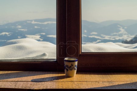Photo for Close up cup on window sill concept photo. Cozy morning. Front view photography with snowy winter landscape on background. High quality picture for wallpaper, travel blog, magazine, article - Royalty Free Image