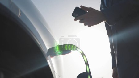 3d Animation of Businessman attaching power cable to electric car. Electric vehicle recharging battery charging port. Unrecognizable man charging electric car at charging station using smart phone app