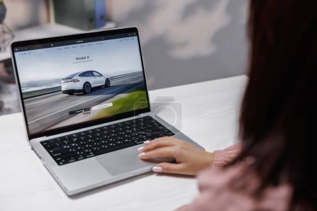 Photo for CALIFORNIA, USA - NOVEMBER 14, 2022: Tesla website, buying a car online. Woman using laptop computer ordering Tesla model X Plaid and full self-driving autopilot. Screen with Website Tesla Company. - Royalty Free Image