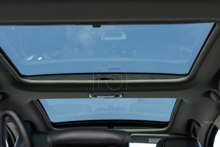Téléchargez les photos : Toit ouvrant en verre panoramique dans la voiture moderne. Vue panoramique à l'intérieur de la voiture - double trappe de toit ouvrant avec verre teinté. Toit ouvrant panoramique coulissant et sièges en cuir luxueux. - en image libre de droit
