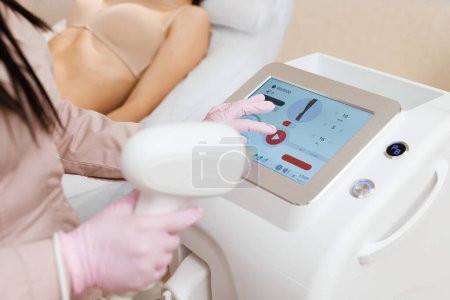 Photo for Therapist checking laser hair removal machine at aesthetic clinic. Woman beautician using laser epilation machine in beauty salon. - Royalty Free Image