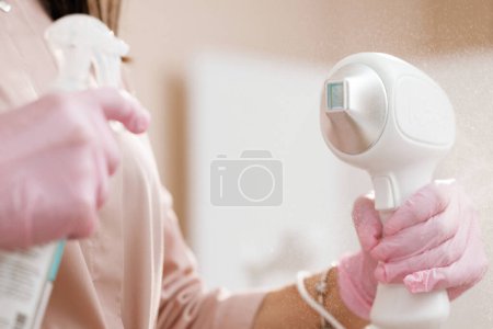 Photo for Female cosmetologist hands holding laser device. Close up of female beautician in sterile gloves using diode laser hair removal machine. Esthetician preparing equipment for epilation procedure. - Royalty Free Image
