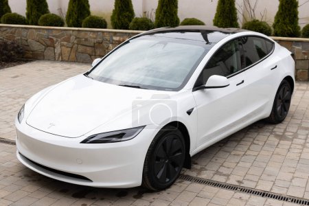 Photo for Lviv, Ukraine - March 23, 2024: White Tesla Model 3 highland electric car in showroom, trends in use EV in contemporary Europe, latest technologies in automotive industry, environmentally sustainable. - Royalty Free Image
