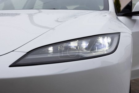 Foto de Lviv, Ucrania - 23 de marzo de 2024: Nuevo Tesla Model 3 highland electric car close up of super bright and modern led matrix headlight lamps. Faros delanteros de matriz. Faro de coche de lujo moderno. - Imagen libre de derechos