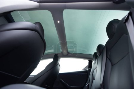 Téléchargez les photos : Toit ouvrant en verre panoramique dans la voiture électrique moderne. Toit ouvrant propre et vue sur le ciel de l'intérieur ou intérieur de la voiture. La vue depuis le coffre de voiture vide avec des sièges arrière. - en image libre de droit