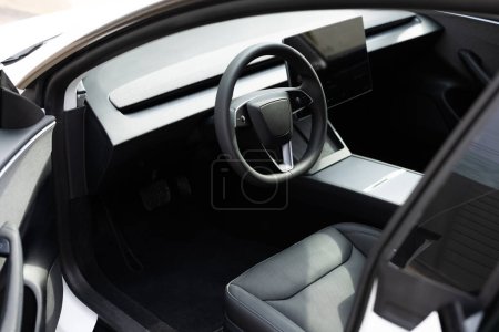 Photo for Steering wheel of a electric vehicle, interior cockpit, electric buttons, digital speedometer, front seats, textile, windows, console, gear shift. Car dashboard with a digital touchscreen. - Royalty Free Image