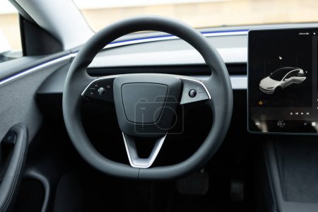 Close up of steering wheel of a new electric vehicle, interior cockpit, electric buttons, digital speedometer. Electric car control devices. Cruise control buttons, speed limitation, cars signal.