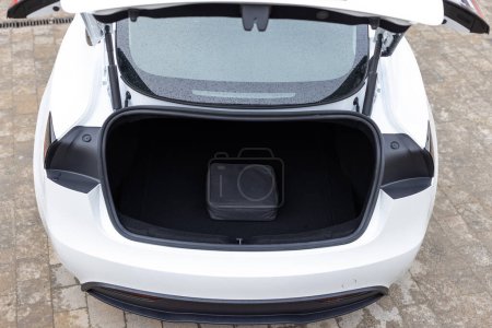 Portable in-cable charging box for electric car charging lying in car trunk. Electric car charger in car trunk. Trunk with charging cables. Modern interior.