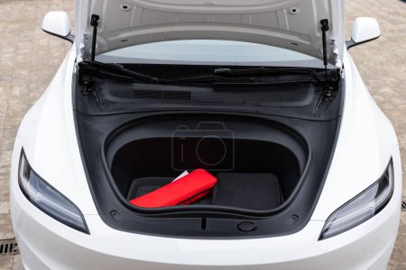 Car trunk for charging cables. Front trunk of white electric vehicle , front trunk details. Modern electric car with open trunk. Car boot is open. Rental car service