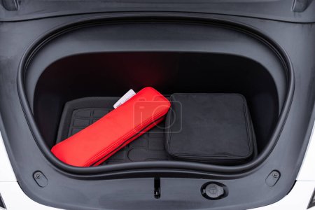 Front trunk or frunk under the hood lockable waterproof storage compartment of modern electric car parked outdoor. Car trunk for charging cables. Modern electric car with open trunk.