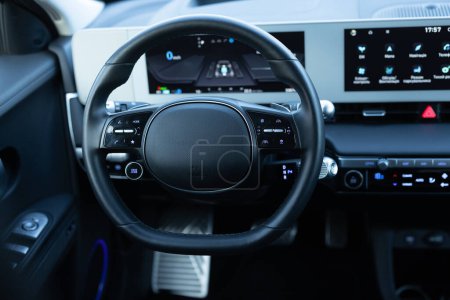 Steering wheel of electric vehicle, interior, cockpit, electric buttons. Autonomous car. Driverless car. Self-driving vehicle. Empty cockpit electric vehicle, Head Up Display and digital speedometer.