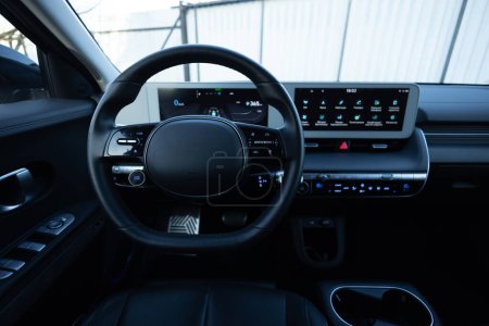 Close up of steering wheel of a new electric vehicle, interior cockpit, electric buttons, digital speedometer. Electric car control devices. Cruise control buttons, speed limitation, cars signal.
