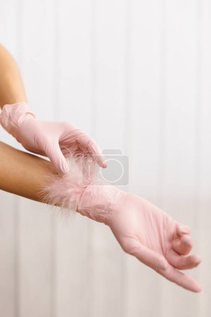 Frauenhände mit weicher Feder. Körperpflege. Feder zu weiblicher Hand auf weißem Hintergrund. Konzept der Leichtigkeit und Sauberkeit. Pflege für die Haut.