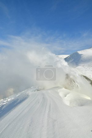 Rauch steigt aus der schneebedeckten Winterlandschaft auf. Vulkan Tokachi, Hokkaido, Japan. Hochwertiges Foto