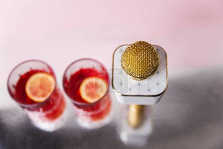 tête de microphone et deux verres de cocktail rose sur un fond rose réfléchissant foyer sélectif isolé avec espace de copie. Concept de karaoké 