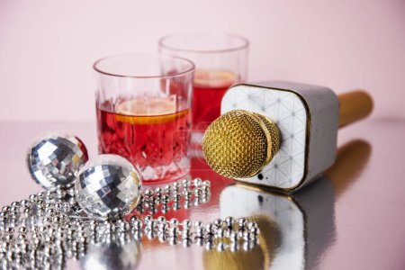 Deux verres de cocktail rouge au citron et microphone sur fond rose concept karaoké