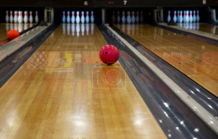 Bowling rote Kugel und Pins auf der Bowlingbahn, selektiver Fokus, Kopierraum. Erreichen des Ziels, gewinnendes Konzept