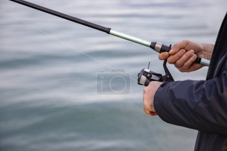Photo for Fisherman holding a fishing rod on the background of the sea - Royalty Free Image