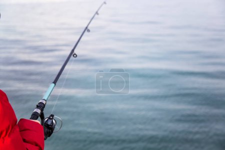 Photo for Fisherman holding a fishing rod on the background of the sea - Royalty Free Image