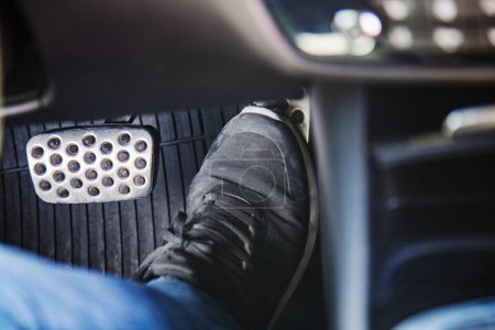 Par de zapatillas negras en el suelo en un coche presionando el pedal de gas, conduciendo cuidadosamente el concepto de coche