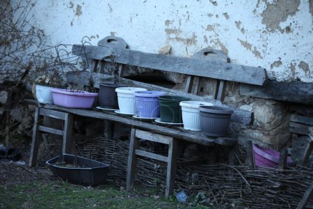 Téléchargez les photos : Un vieux banc en bois avec des pots de fleurs dessus, un banc devant une vieille maison délabrée - en image libre de droit