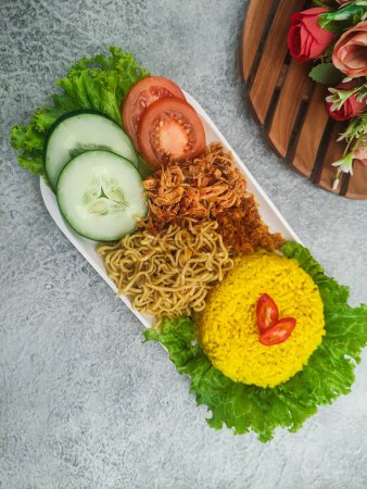 Téléchargez les photos : Nasi Kuning, une cuisine traditionnelle indonésienne. Riz jaune servi avec nouilles, poulet et légumes râpés - en image libre de droit