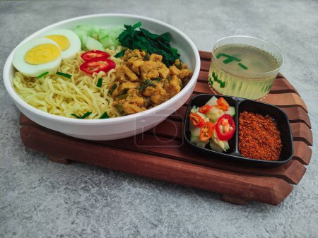 Foto de Mie Ayam, una comida callejera indonesia. Fideos completados con cubitos de pollo, rodajas de huevo y verduras servidas en un tazón blanco. Enfoque selectivo - Imagen libre de derechos