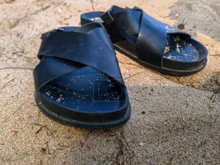 Foto de Sandalias negras en la arena de la playa - Imagen libre de derechos