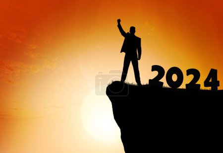 Photo for The concept of Victory in the new year 2024. A man stands with his hands raised up against the background of a sunset the number 2024. - Royalty Free Image