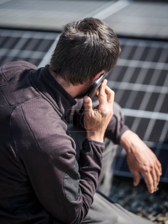 Foto de Rooftop worker making phone calls with mobile phone during installation of solar panels - Imagen libre de derechos