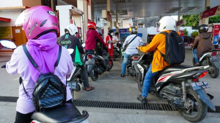 Foto de Makassar, June 2nd, 2022: Motorcycle riders queue at one of Pertamina (State Oil and Natural Gas Mining Company) gas stations in Makassar - Imagen libre de derechos