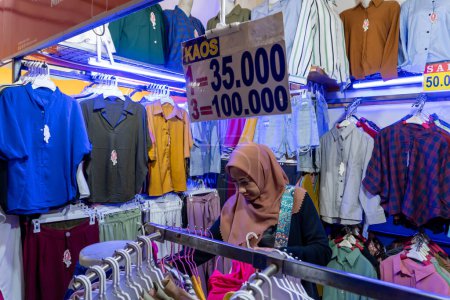 Téléchargez les photos : Choix de mode : Une femme portant un hijab choisit ses vêtements à un comptoir de vêtements dans la région touristique de Kota Tua le 23 janvier 2023 - en image libre de droit