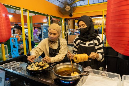 Foto de 23 de enero de 2023: vendedores friendo rosquillas y takoyaki en medio del ajetreo y el bullicio del distrito turístico de kota tua en el norte de Yakarta - Imagen libre de derechos