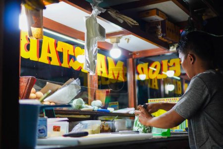 Foto de Enero 26, 2023: Experto vendedor de martabak ingeniosamente ensamblando rellenos de huevo y verduras en Yakarta para una fritura deliciosa - Imagen libre de derechos