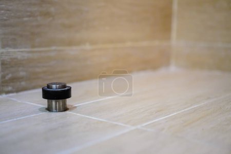 Photo for Stainless door stop with black rubber behind the door on the floor. Protection of walls, baseboards against door impact damage - Royalty Free Image