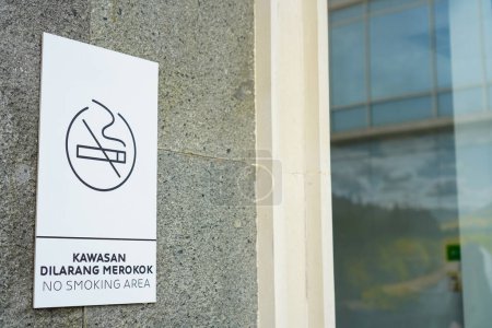 "Rauchverbot in diesem Bereich" steht auf einer Außenwand aus Stucksteinen