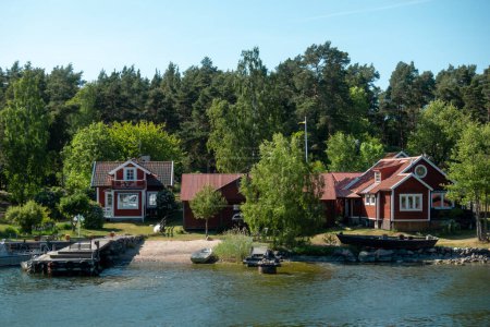 Foto de Típica casa roja sueca con adornos blancos por la orilla del mar en idílico paisaje de verano - Imagen libre de derechos