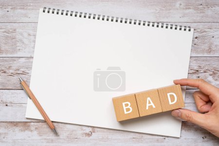 Téléchargez les photos : Blocs en bois avec "BAD" texte de concept, un stylo et un carnet. - en image libre de droit