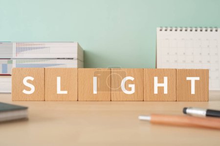 Foto de Bloques de madera con texto "SLIGHT" de concepto, bolígrafos, cuadernos y libros. - Imagen libre de derechos