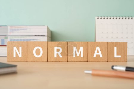 Photo for Wooden blocks with "NORMAL" text of concept, pens, notebooks, and books. - Royalty Free Image