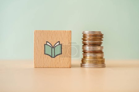 Photo for A wooden block with a book icon and coins. - Royalty Free Image