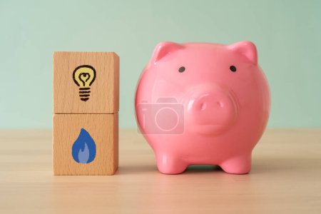 Photo for A pink piggy bank and wooden blocks with a light bulb and gas icon. - Royalty Free Image